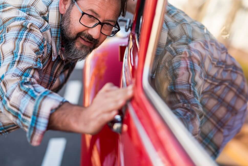 Mann inspiziert akribisch die Oldtimerkarosserie